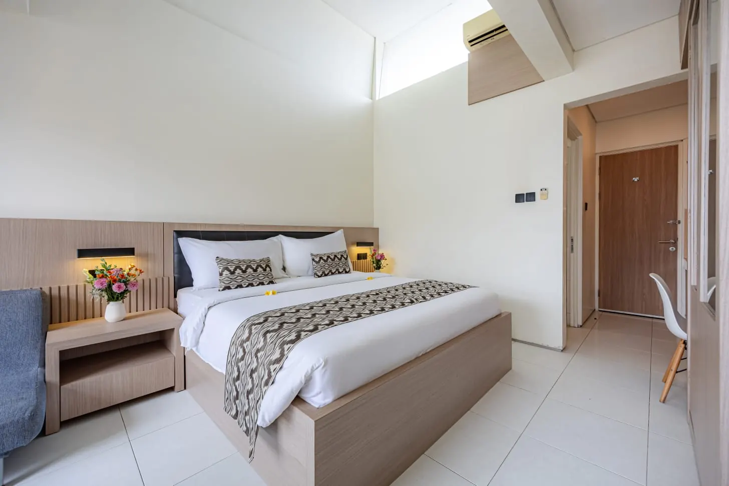 Kamar Master Suite dengan perabot kayu berwarna terang dan langit-langit tinggi